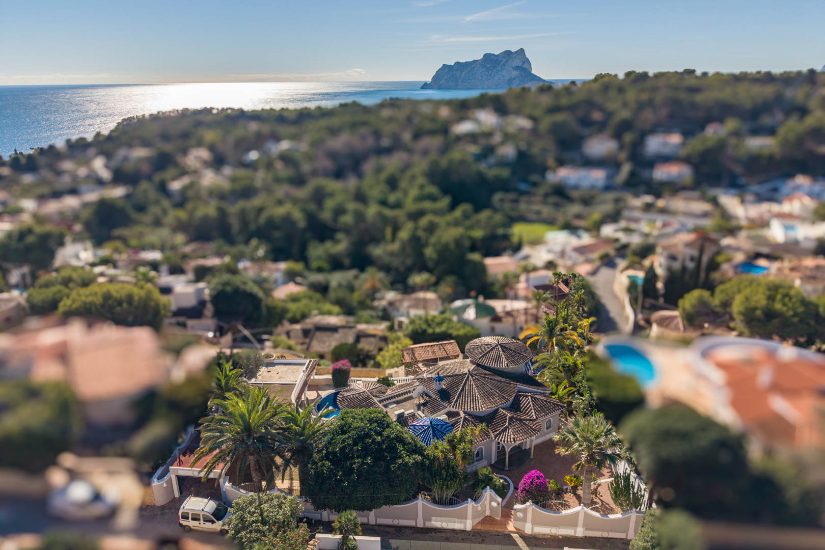Luchtfoto van de villa in Benissa met karakteristieke pannendaken en een volgroeide tuin, uitkijkend over de Middellandse Zee en de Peñón de Ifach.