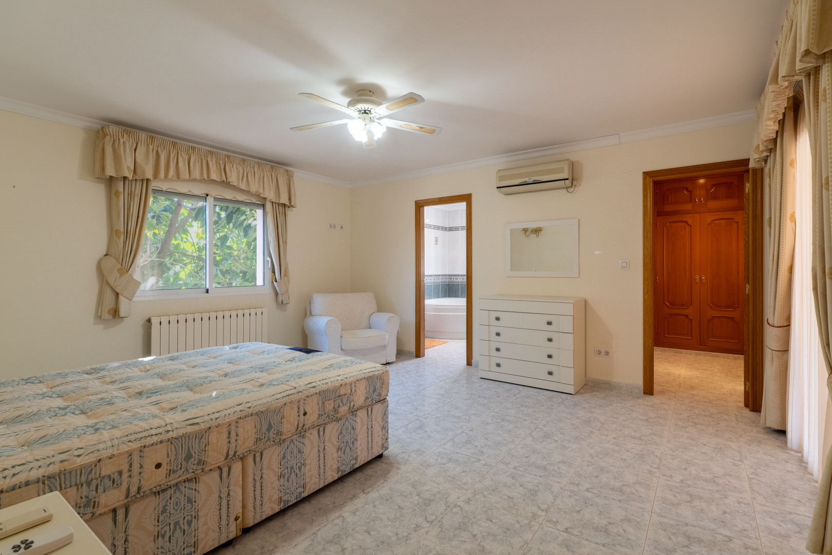 Hoofdslaapkamer met en-suite badkamer en inloopkast. Voorzien van een keramische tegelvloer, airconditioning, plafondventilator en houten deurkozijnen.