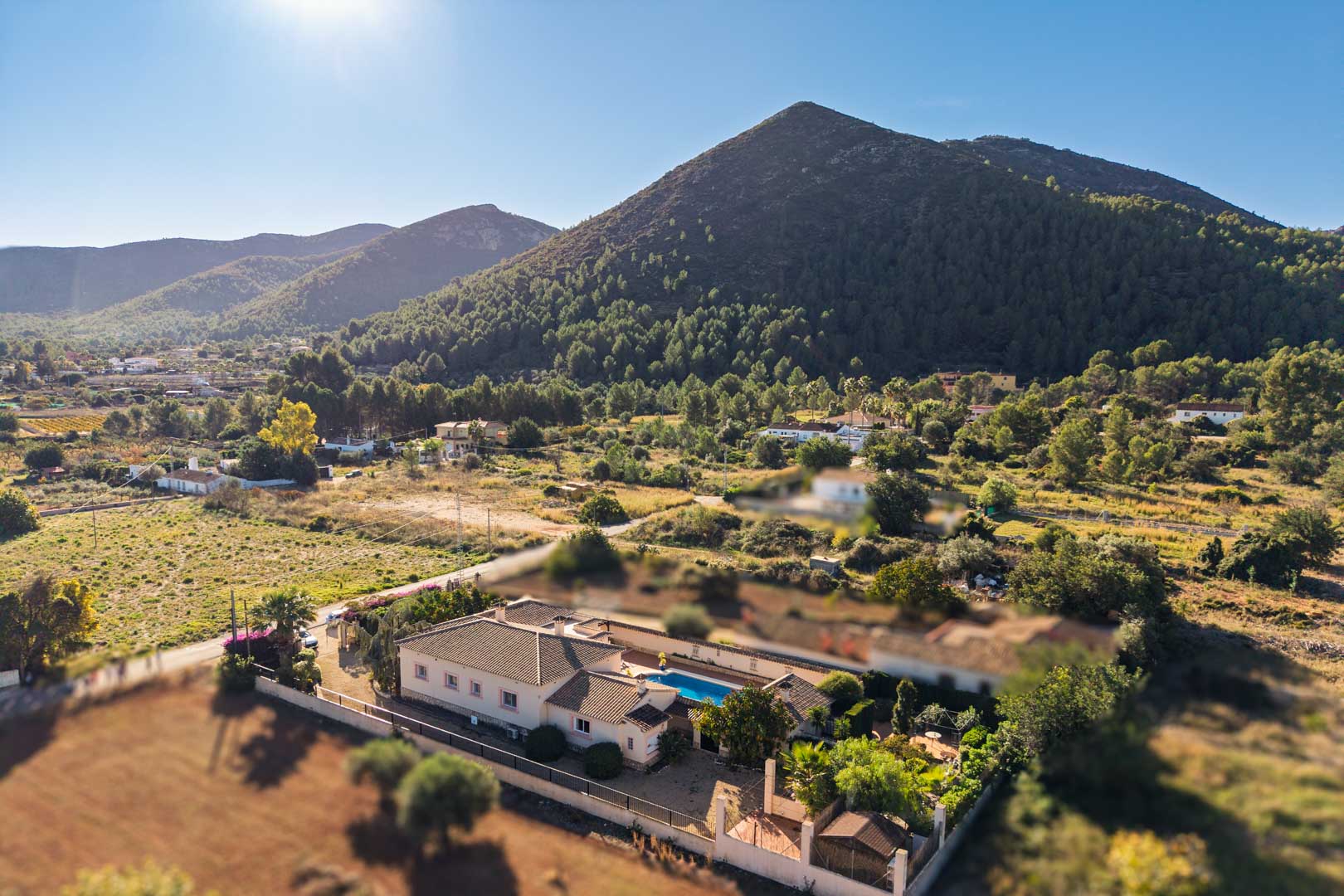 Luchtfoto van de mediterrane villa in Jalón, met een centraal gelegen zwembad en panoramisch uitzicht op de omliggende bergen.