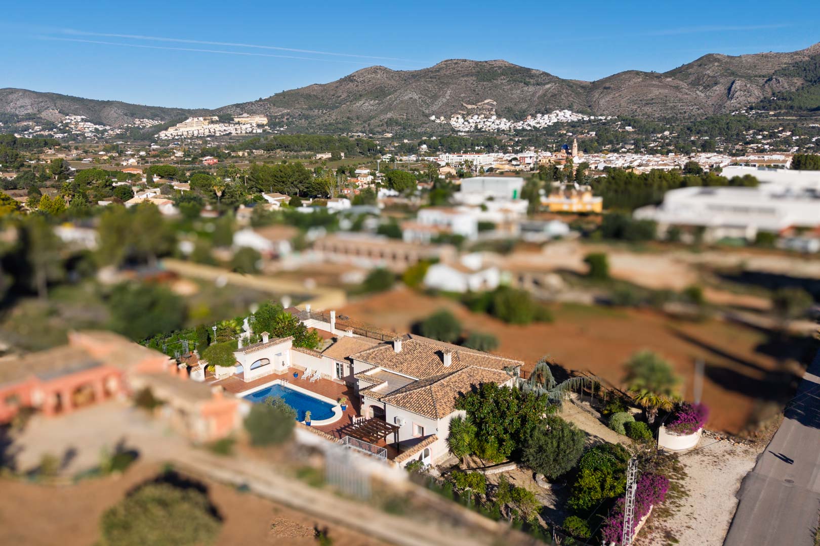 Luchtfoto van de mediterrane villa met privézwembad en pannendak, met een weids uitzicht over het dorp Jalón en de omliggende bergen.