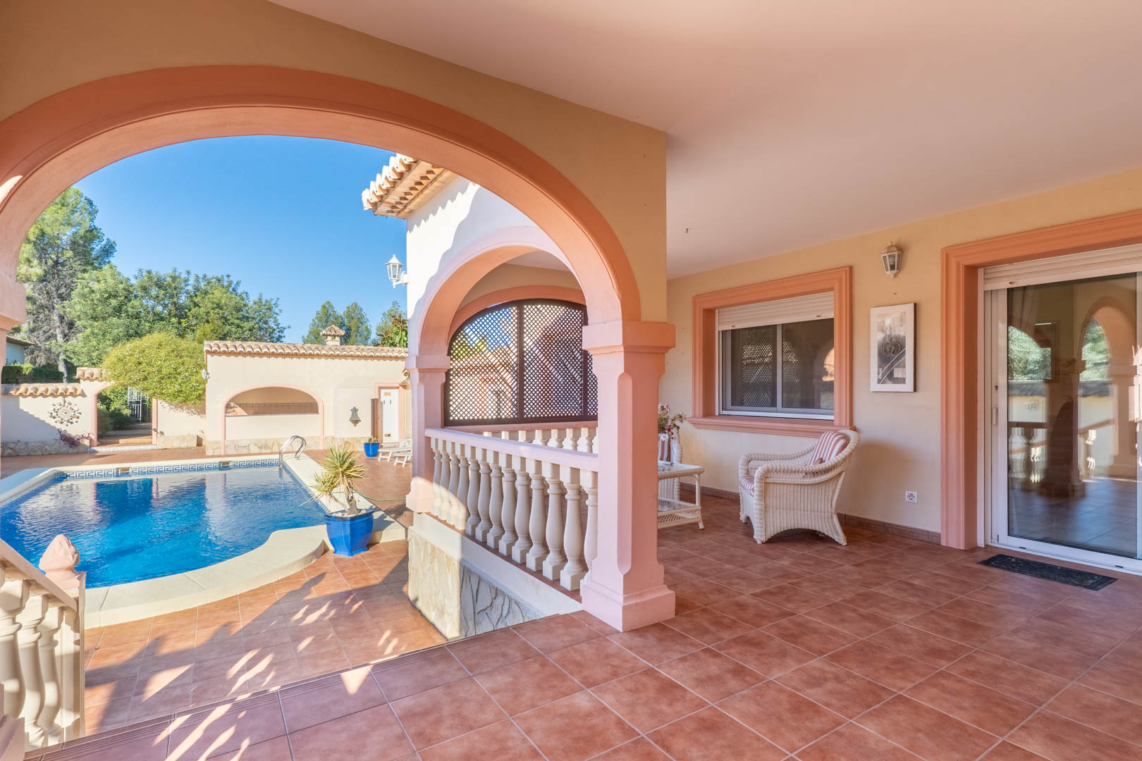 Ruim overdekt terras met mediterrane bogen en terracotta vloertegels, uitkijkend op het privézwembad met directe toegang tot de woning.