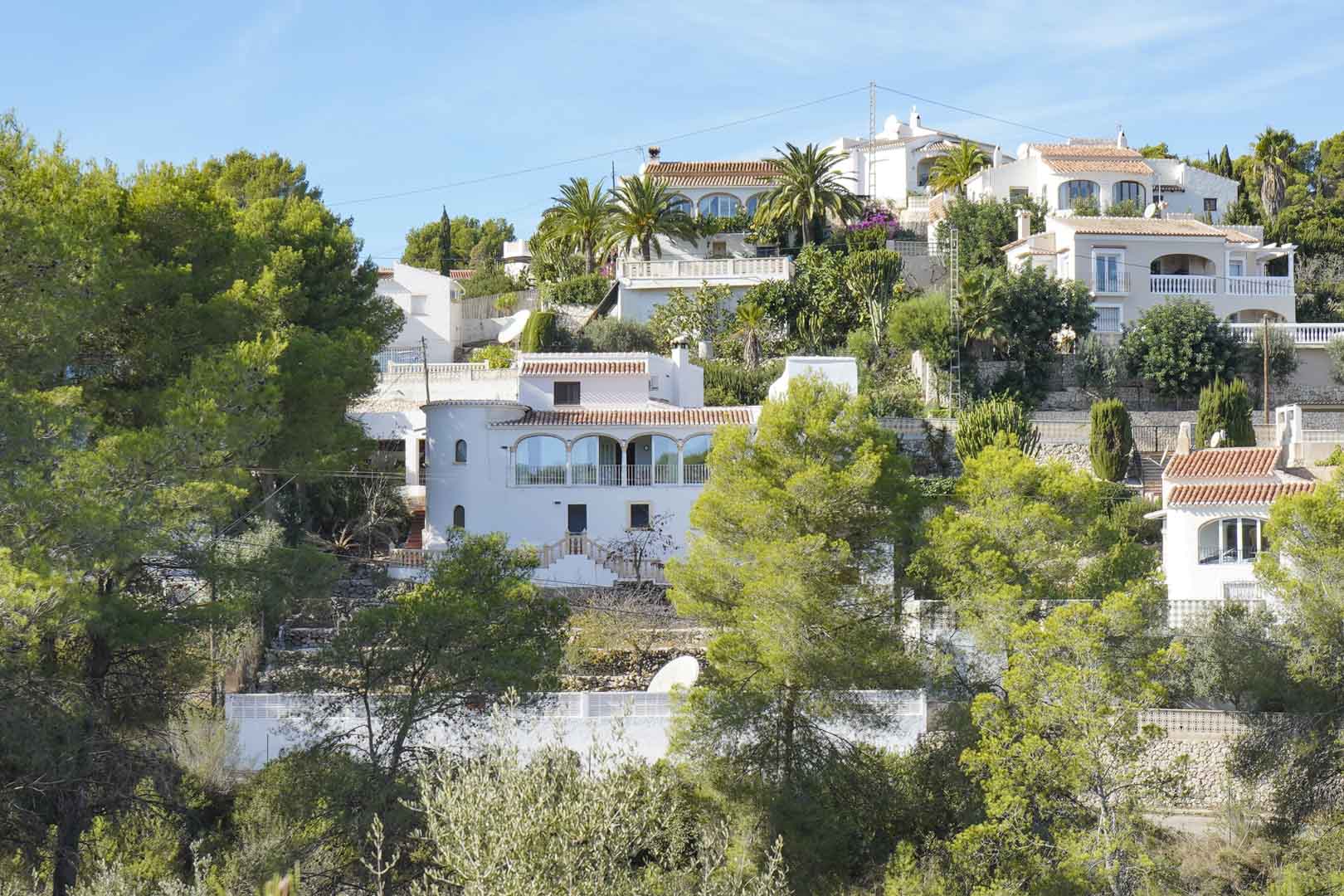 Exterieur van de mediterrane villa op een beboste heuvel, met witte gevel, beglaasde naya met bogen en een traditionele ronde toren.