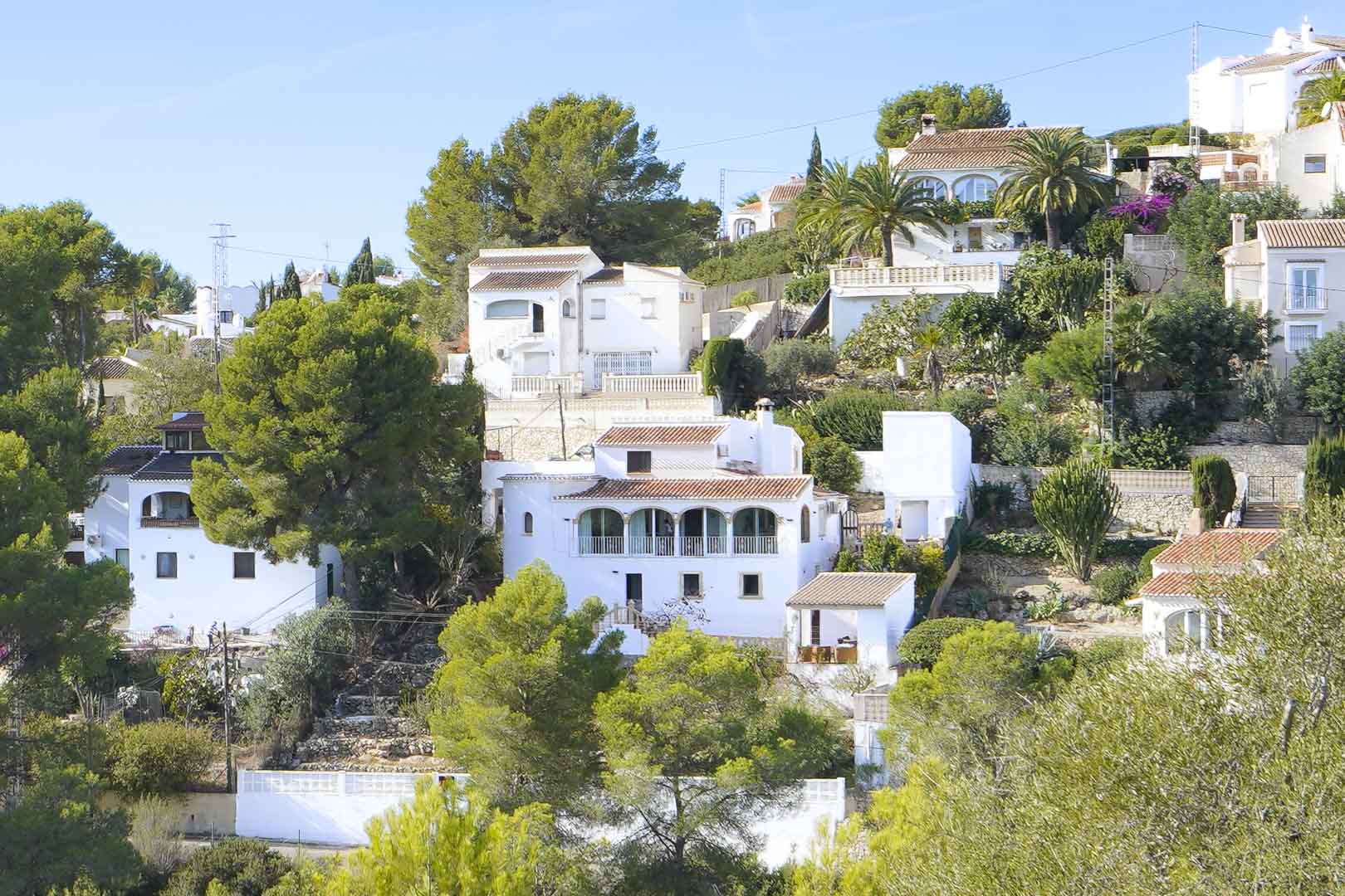 Exterieur van de villa met meerdere niveaus, een traditionele naya met bogen, witte gevels en een bosrijke mediterrane omgeving in de wijk Pinomar.