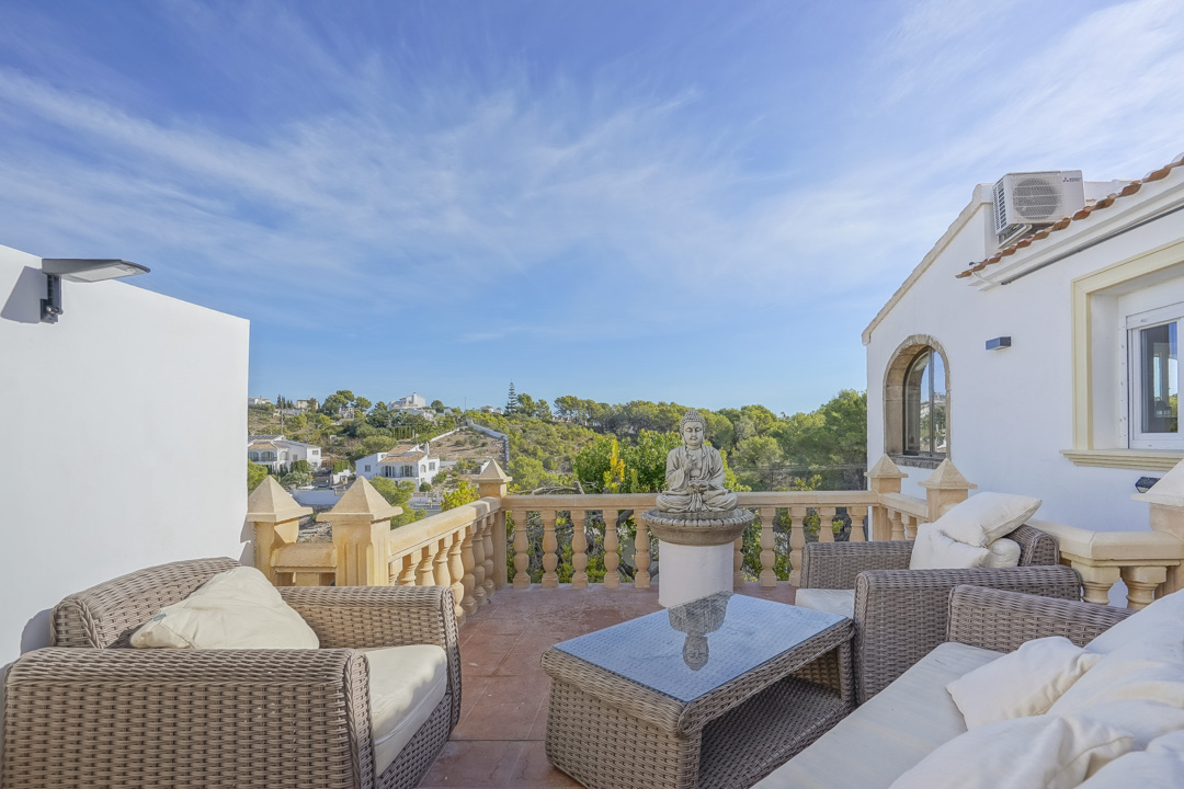 Verhoogd terras met rotan loungeset, traditionele stenen balustrade en vrij uitzicht over de groene heuvels en omliggende villa's in Jávea.
