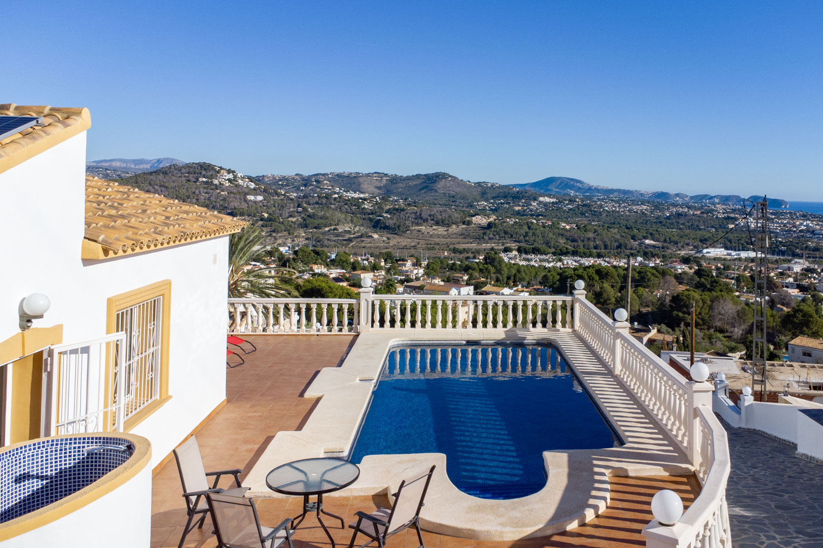 Buitenterras met zwembad, klassieke balustrades en panoramisch uitzicht op de kust van Calpe en de omliggende bergen.
