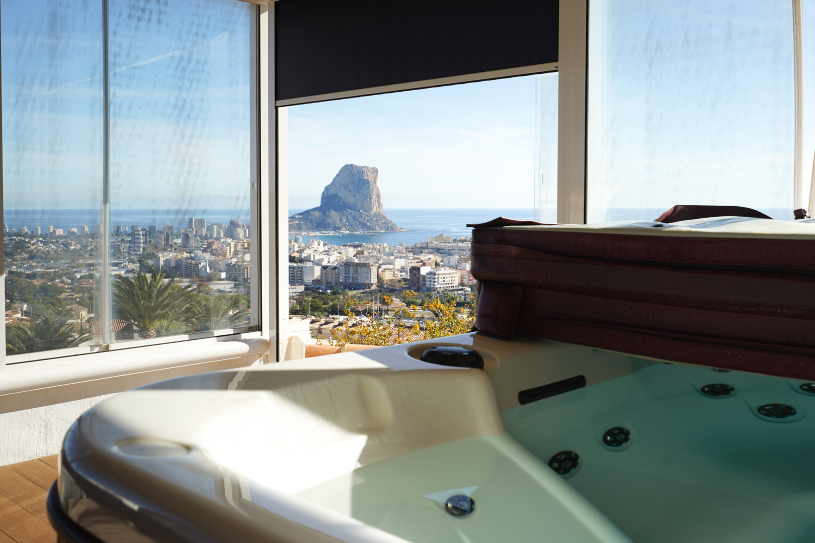 Jacuzzi op de bovenverdieping met glazen wanden en panoramisch uitzicht op de Peñón de Ifach, de skyline van Calpe en de Middellandse Zee.