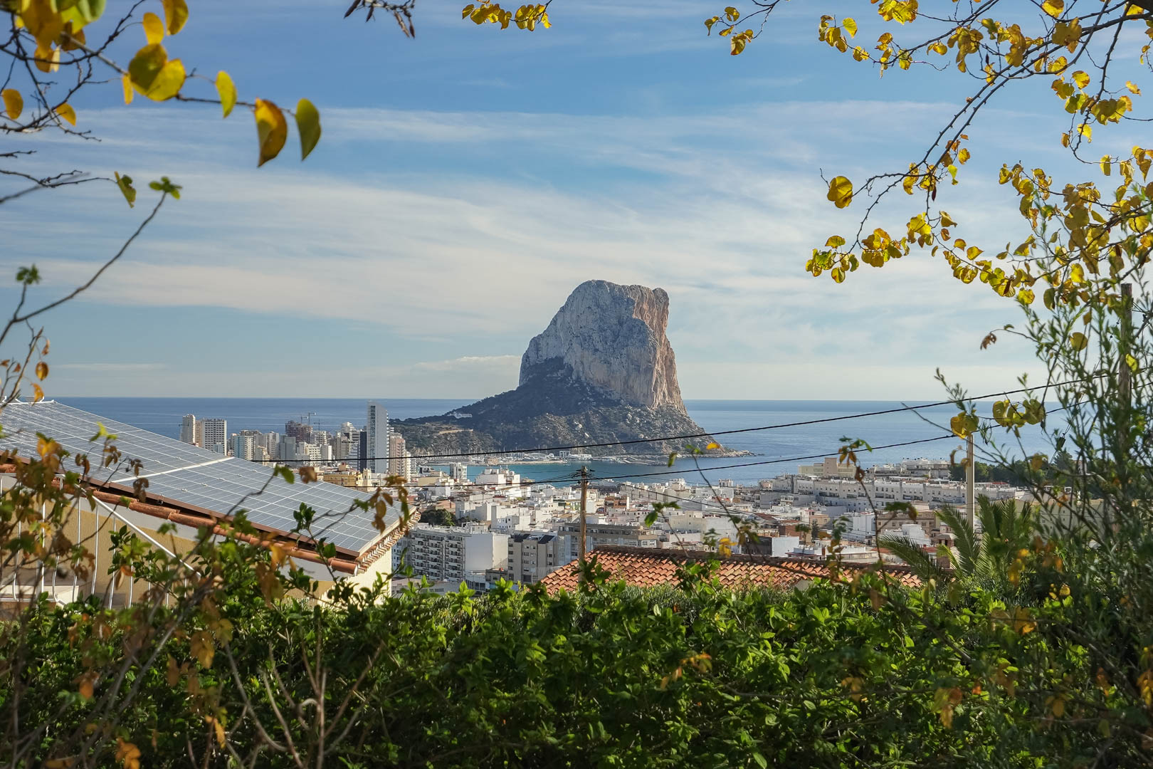 Panoramisch uitzicht op de Peñón de Ifach en de skyline van Calpe, met de zonnepanelen op het dak omgeven door weelderig mediterraan groen.