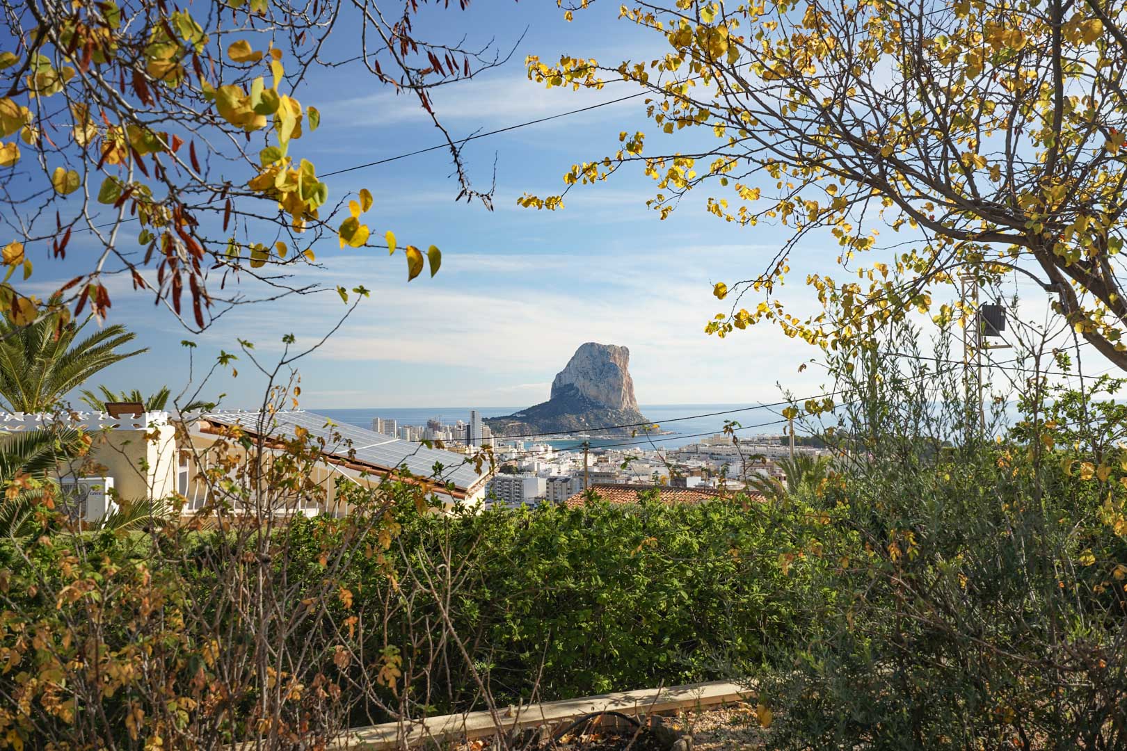 Panoramisch uitzicht op de Peñón de Ifach en de skyline van Calpe, met zicht op de zonnepanelen op het dak en de omliggende mediterrane beplanting.