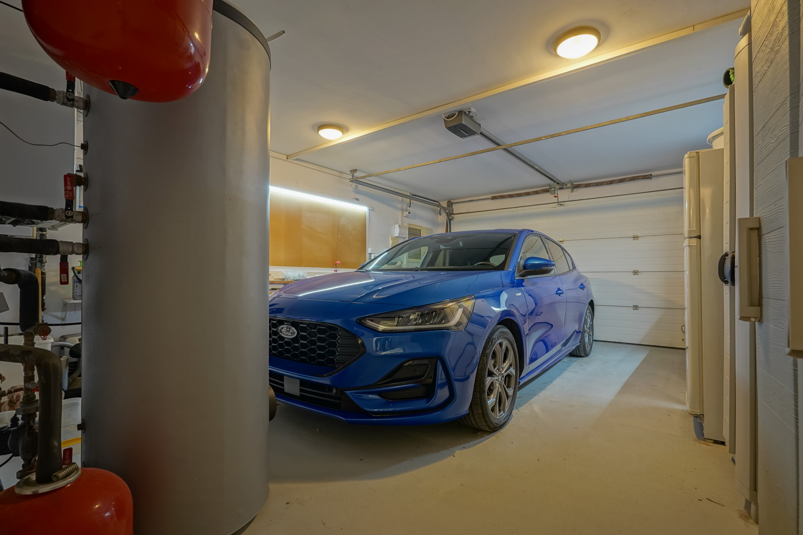 Privégarage met automatische deur, een werkplaats met LED-verlichting en technische installaties waaronder een warmwaterboiler.