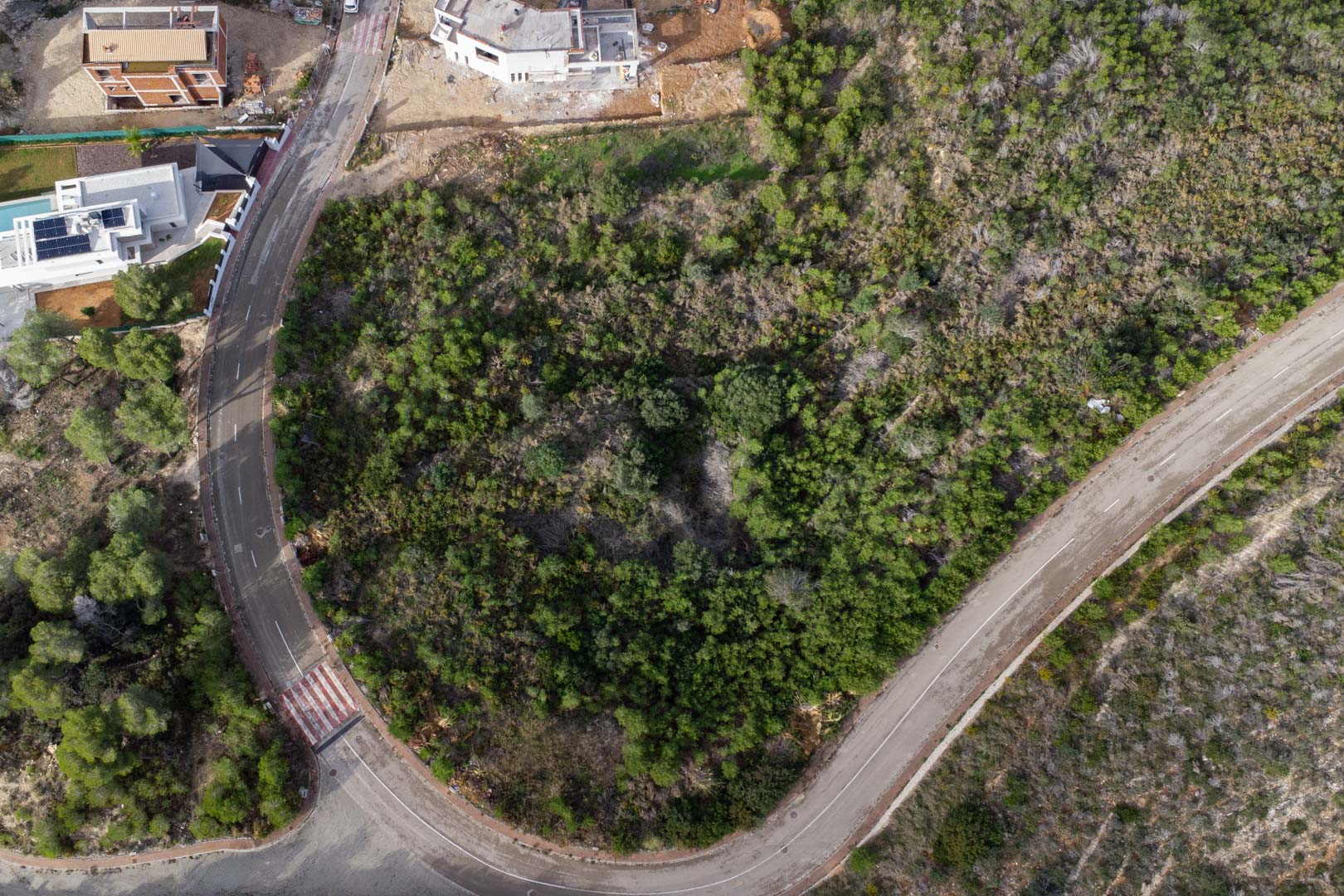 Bovenaanzicht van het stedelijke hoekperceel in Monte Olímpico, direct gelegen aan geasfalteerde wegen met trottoirs en natuurlijke begroeiing.