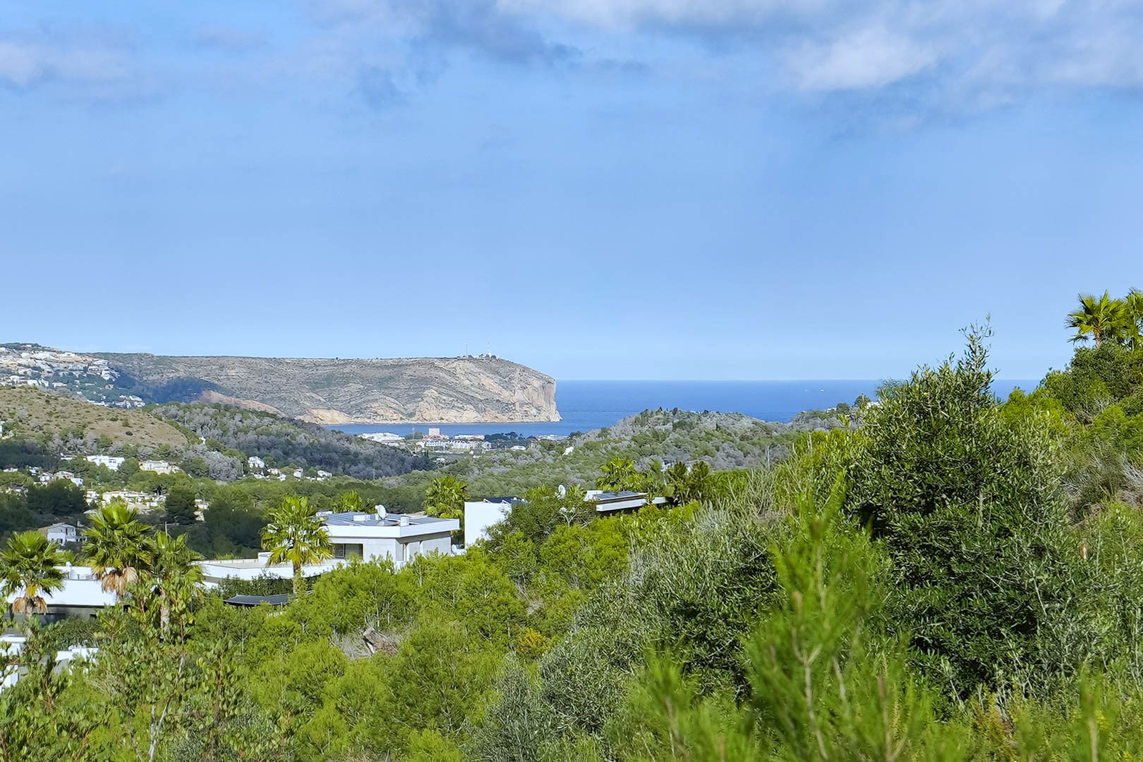 Panoramisch uitzicht vanaf het perceel op de Middellandse Zee en Cabo de San Antonio, omgeven door pijnbomen en moderne villa's.