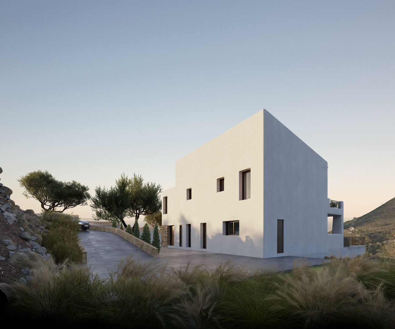 Buitenaanzicht van de villa in Ibiza-stijl met een minimalistische witte gevel, geplaveide oprit en natuurstenen muren geïntegreerd in het landschap van Alcalalí.