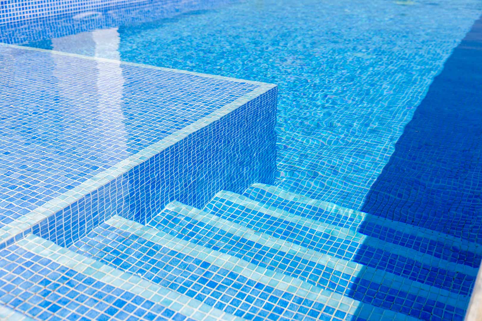 Detailopname van het privézwembad met blauwe mozaïektegels en ingebouwde trappen onder water, wat de helderheid en strakke afwerking accentueert.
