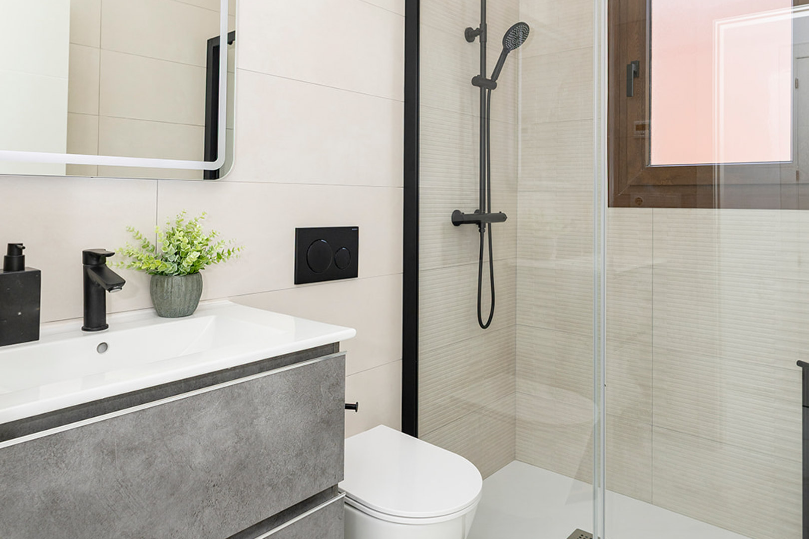 Moderne badkamer met grijs meubel, matzwarte kranen, hangend toilet en glazen douchewand met lineaire reliëftegels.