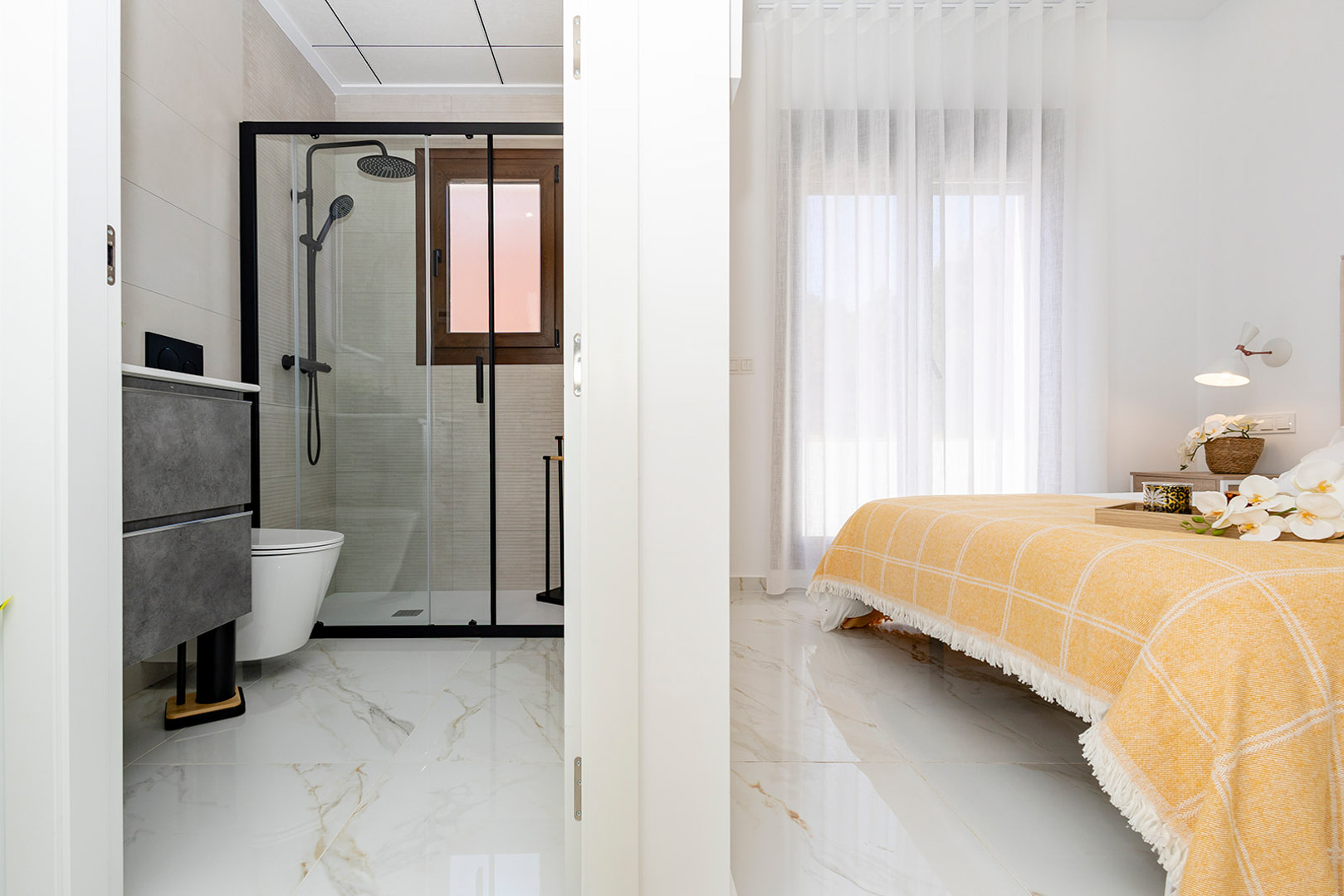 Slaapkamer met geïntegreerde en-suite badkamer, marmerlook porseleinen vloeren en een inloopdouche met moderne zwarte profielen.