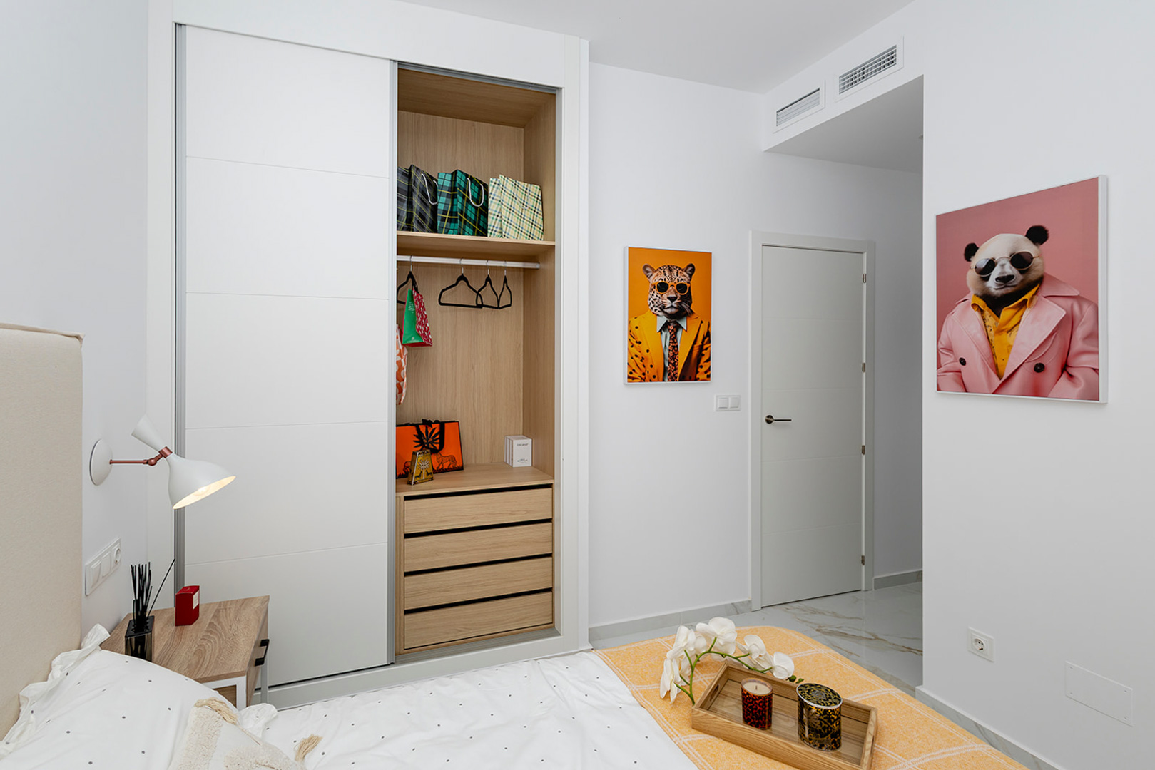 Slaapkamer met inbouwkast voorzien van witte schuifdeuren en een houten interieur. Voorzien van een marmerlook vloer en airconditioning via kanalen.