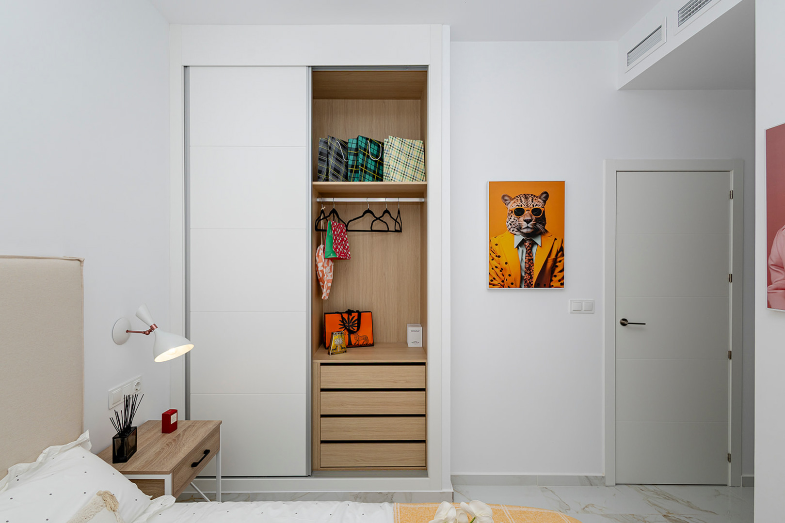 Slaapkamer met inbouwkast voorzien van witte schuifdeuren en houten interieur. De ruimte heeft marmerlook vloertegels en geïntegreerde airconditioning.
