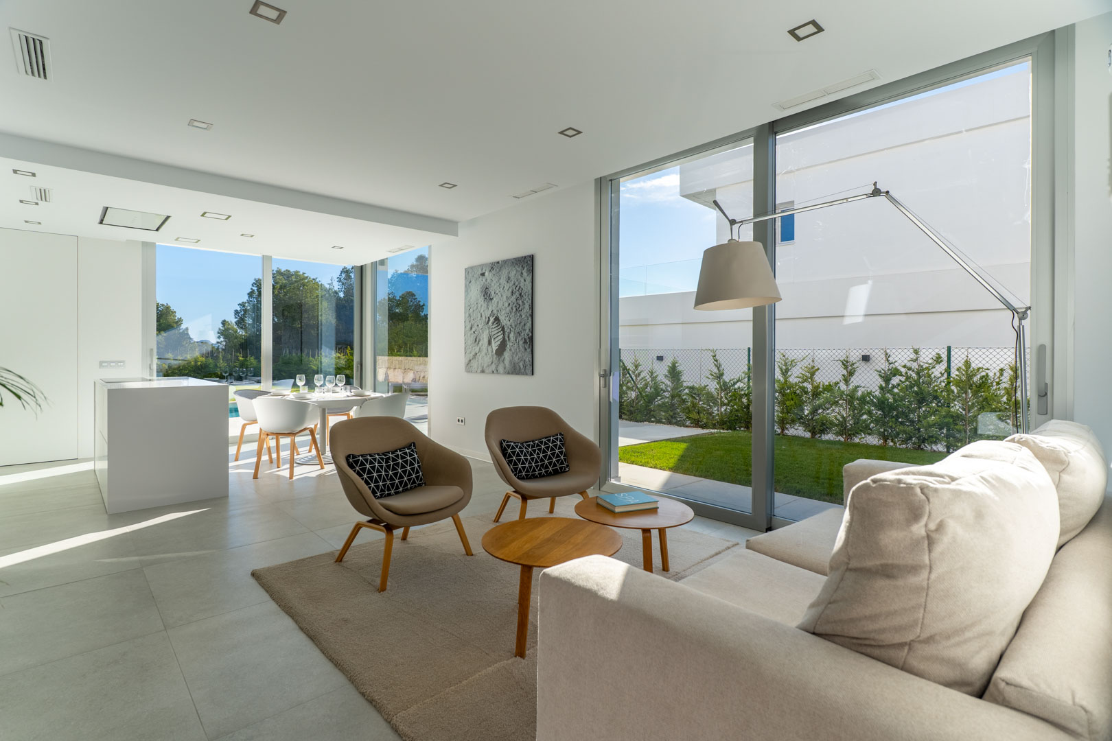 Open woonkamer met kamerhoge glazen schuifdeuren, minimalistisch designmeubilair en een directe verbinding met de privétuin.