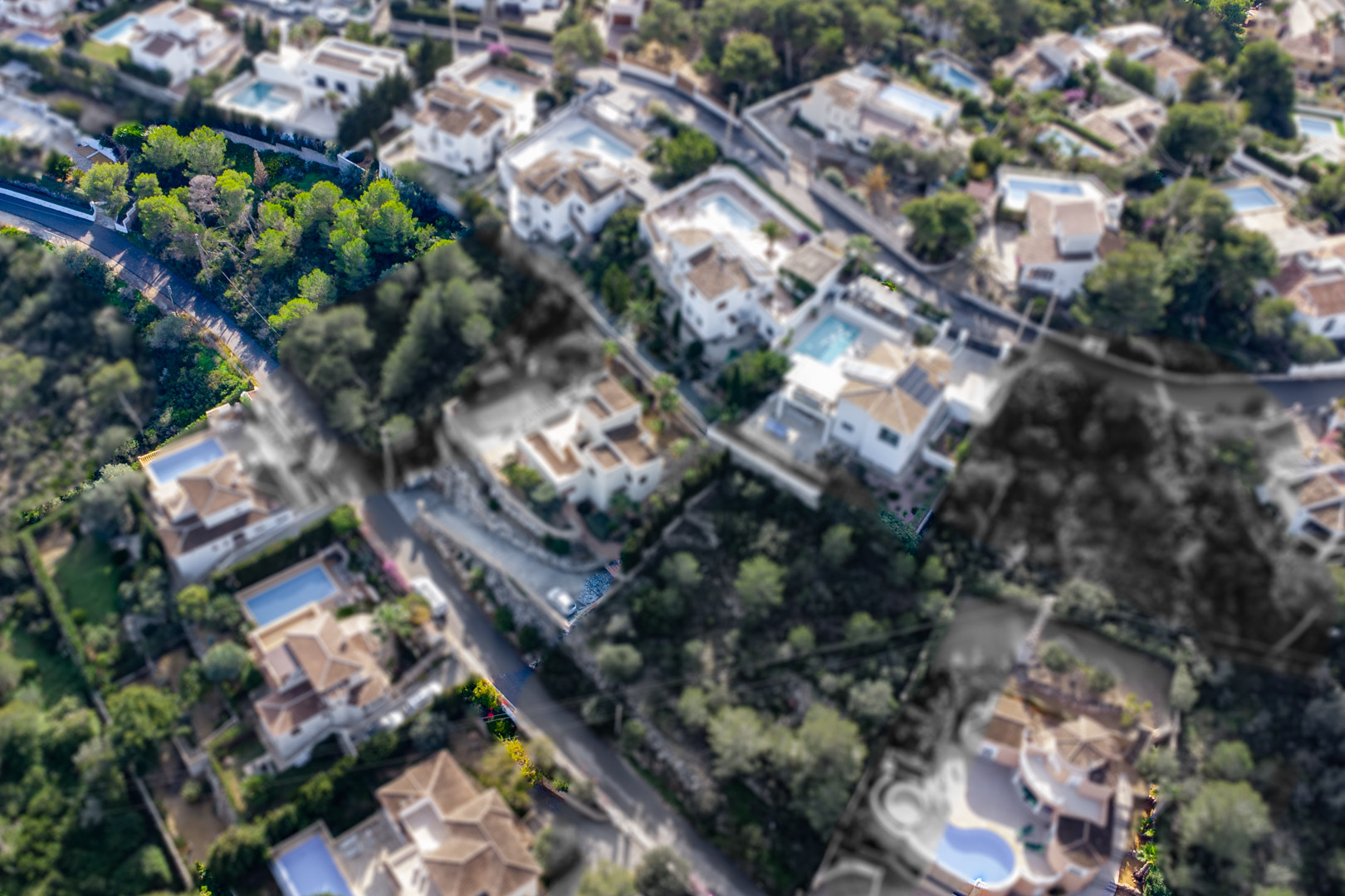 Luchtfoto van het bouwperceel van 1521 m2 op een helling met pijnbomen, gelegen in een gevestigde villawijk nabij de baaien van Granadella en Ambolo.