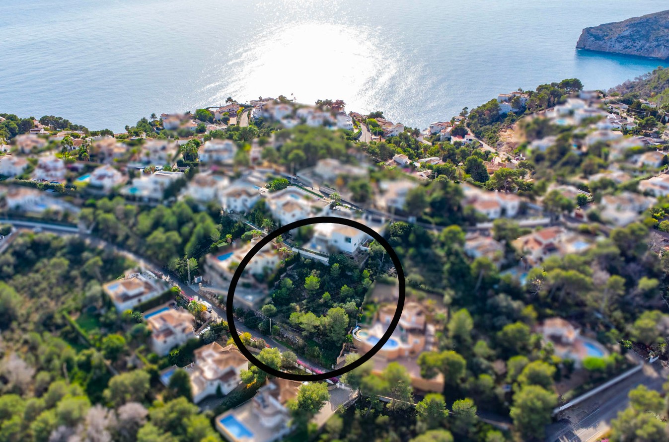 Luchtfoto van het bouwperceel van 1042m2 met pijnbomen en een hellend terrein, gelegen in een rustige woonwijk met uitzicht op de Middellandse Zee.
