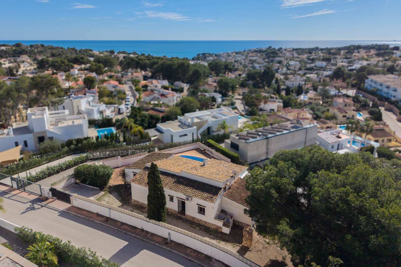 Luchtfoto van de villa in Benissa Costa, met de mediterrane architectuur, het privéterrein met cipressen en een weids uitzicht over de Middellandse Zee.