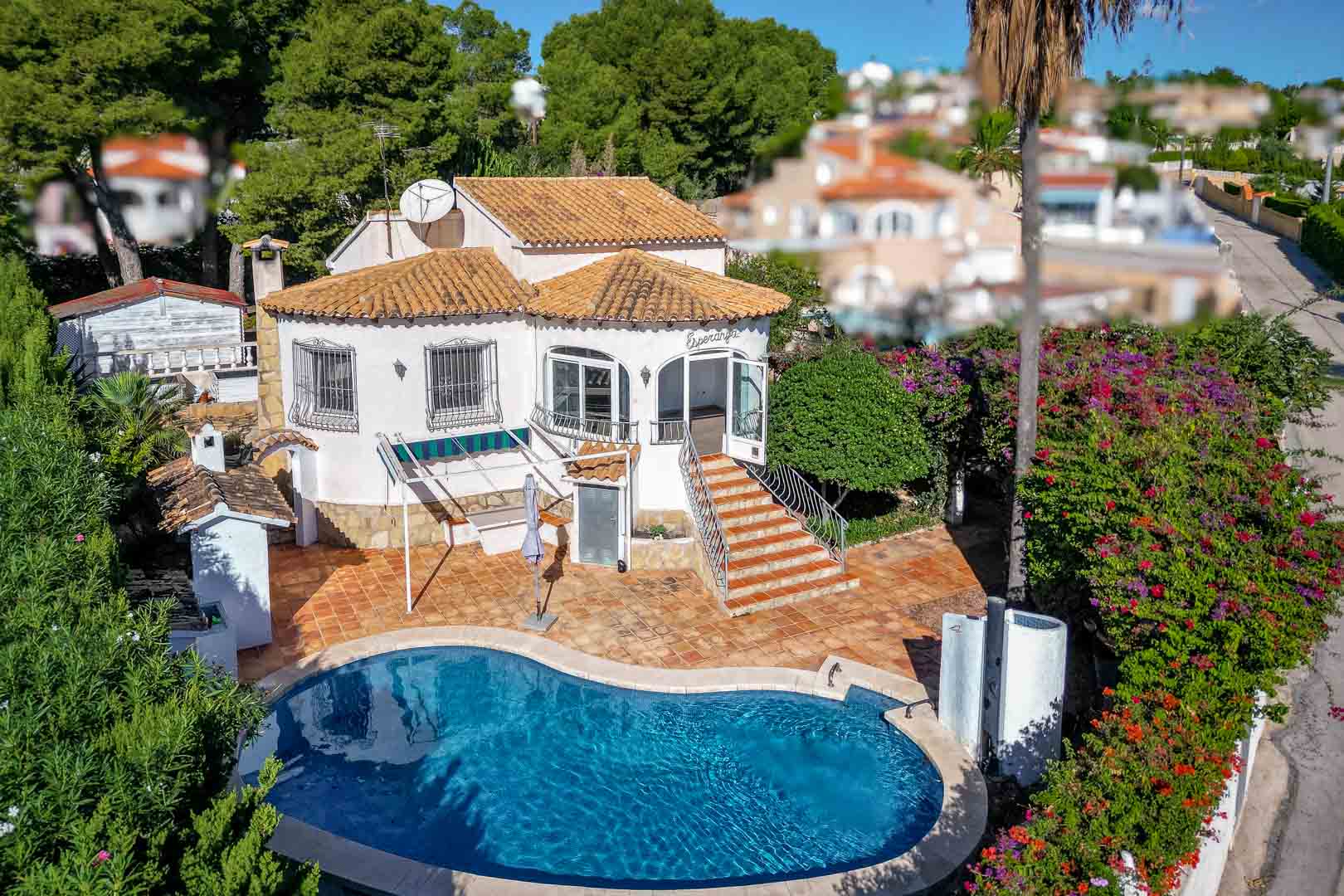 Exterieur van de villa met niervormig zwembad, terracotta terras en trap naar de glazen veranda, omgeven door een volgroeide mediterrane tuin.