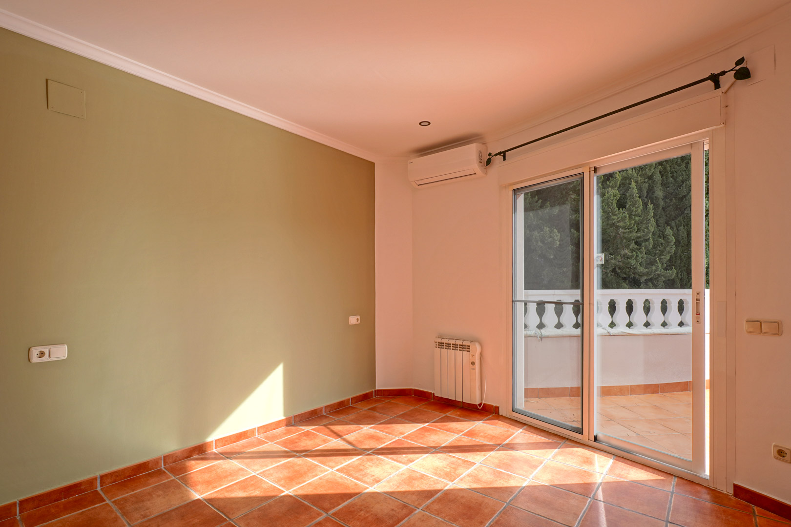 Lichte kamer met groene accentmuur, terracotta tegels en toegang tot het terras. Voorzien van split-airconditioning, elektrische radiator en plafondlijsten.