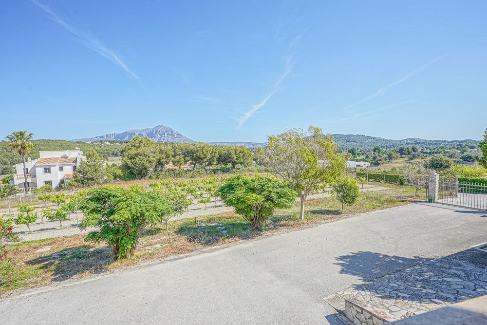 Uitzicht vanaf de oprit op een privévijngaard en het mediterrane landschap met de berg Montgó op de achtergrond.