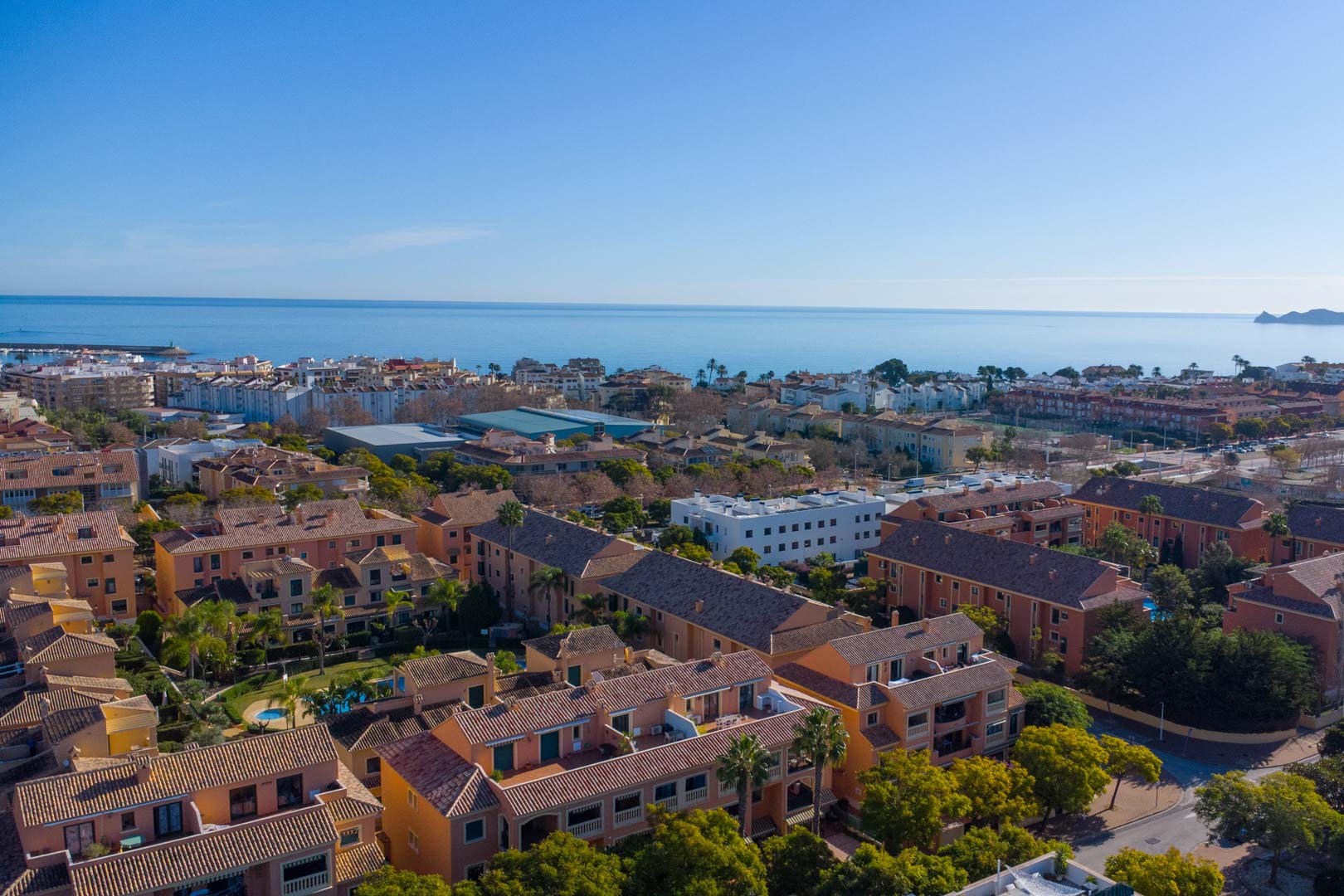Luchtfoto van het Floridamar-complex in Jávea, met de mediterrane architectuur, gemeenschappelijke tuinen en de gunstige ligging nabij de zee en de haven.