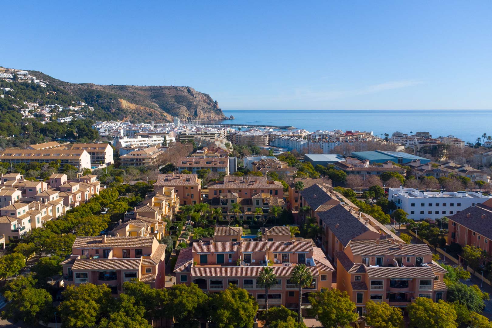 Luchtfoto van het Floridamar-complex in Jávea, met de mediterrane architectuur, groene tuinen en uitzicht op de haven en de Middellandse Zee.