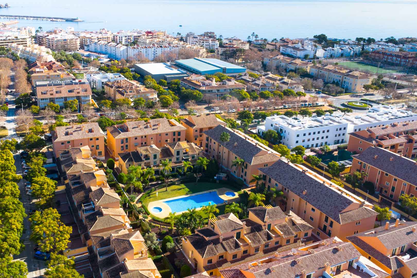 Luchtfoto van het Floridamar-complex in Jávea, met focus op het gemeenschappelijke zwembad, de tuinen en de gunstige ligging nabij de haven en zee.