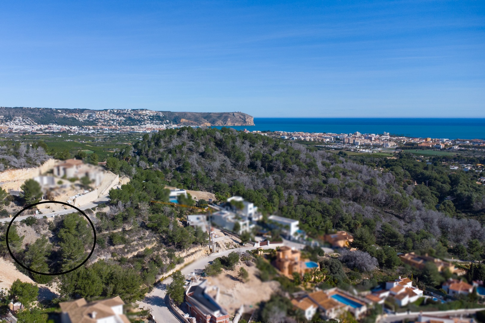Luchtfoto van het hooggelegen perceel in Tosalet 5, omgeven door pijnbomen met panoramisch uitzicht op de Middellandse Zee en de kust van Jávea.