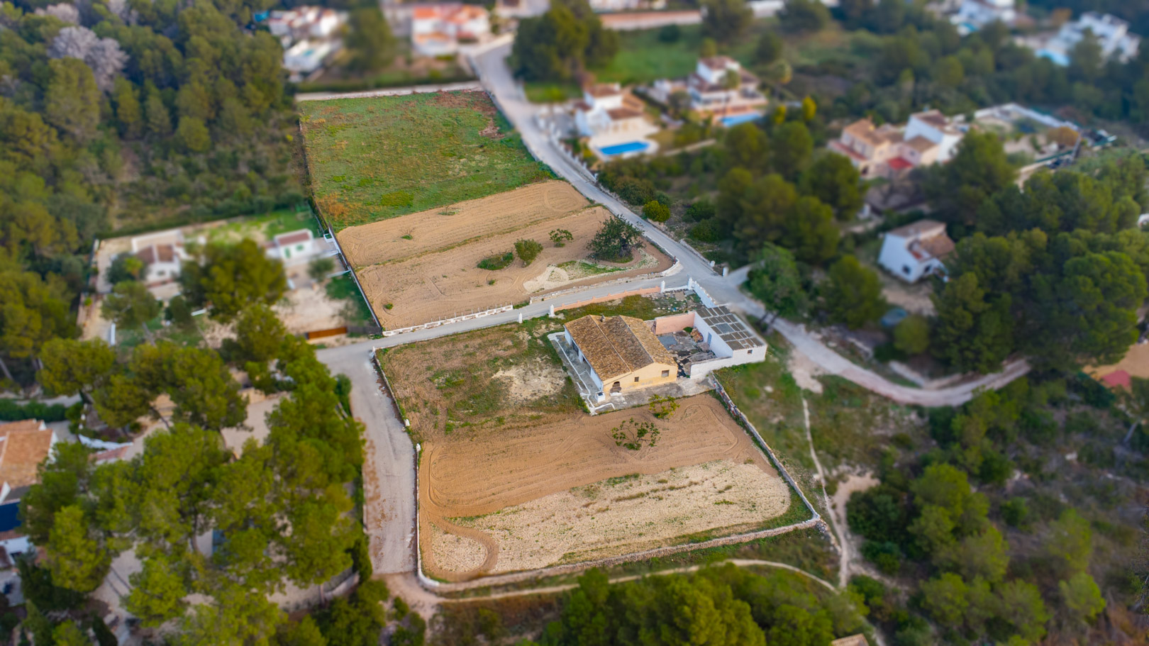 Luchtfoto van de traditionele finca en de uitgestrekte vlakke rustieke percelen, omgeven door mediterrane vegetatie en dennenbossen in Jávea.