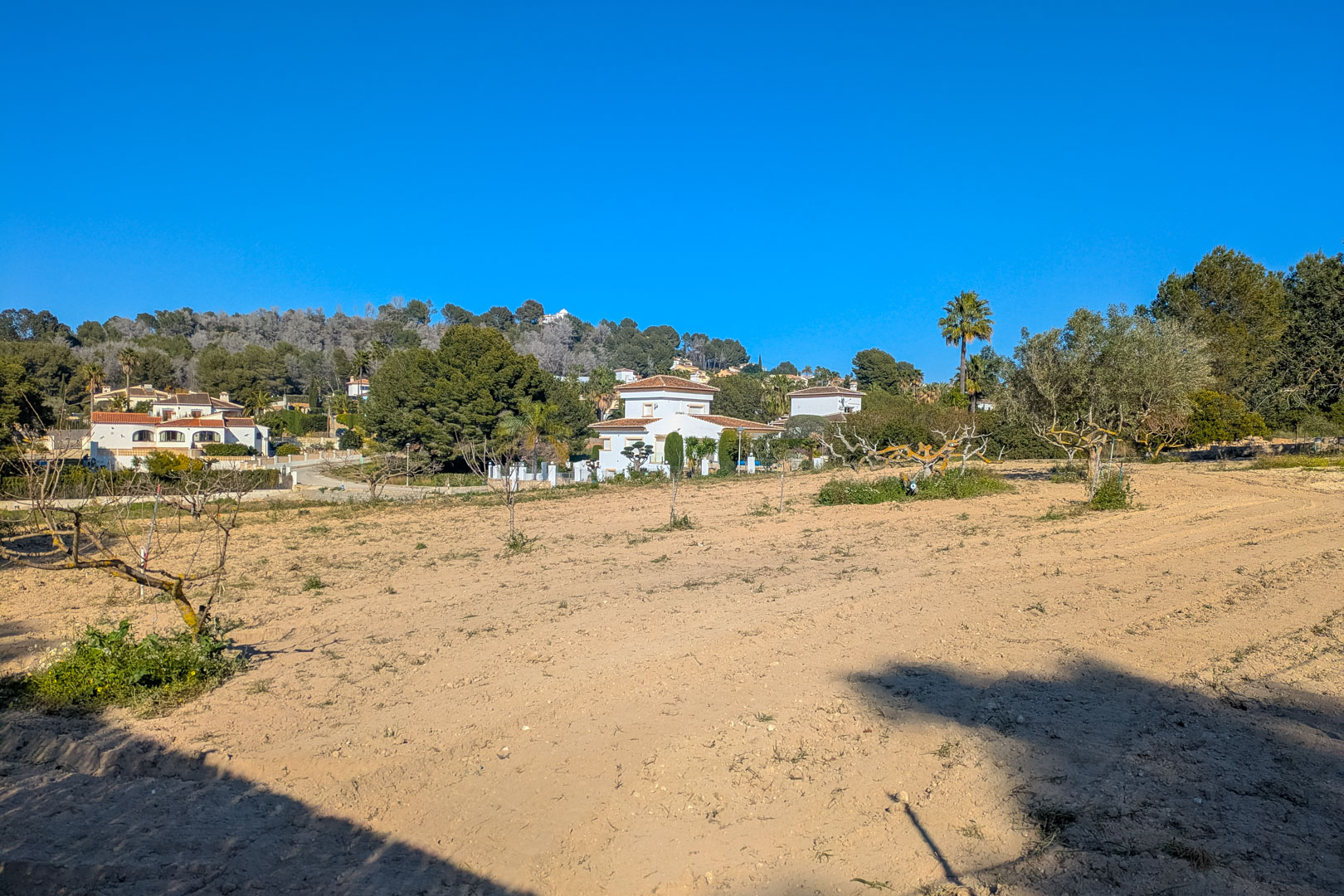 Panoramisch uitzicht op het uitgestrekte vlakke rustieke perceel, omgeven door mediterrane begroeiing met vrij uitzicht op de heuvels en naburige villa's.