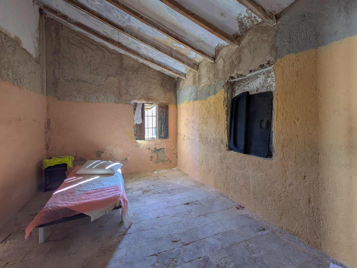 Rustieke binnenruimte met authentieke houten balkenplafonds, originele plavuizen vloeren en muren die wachten op een volledige renovatie.