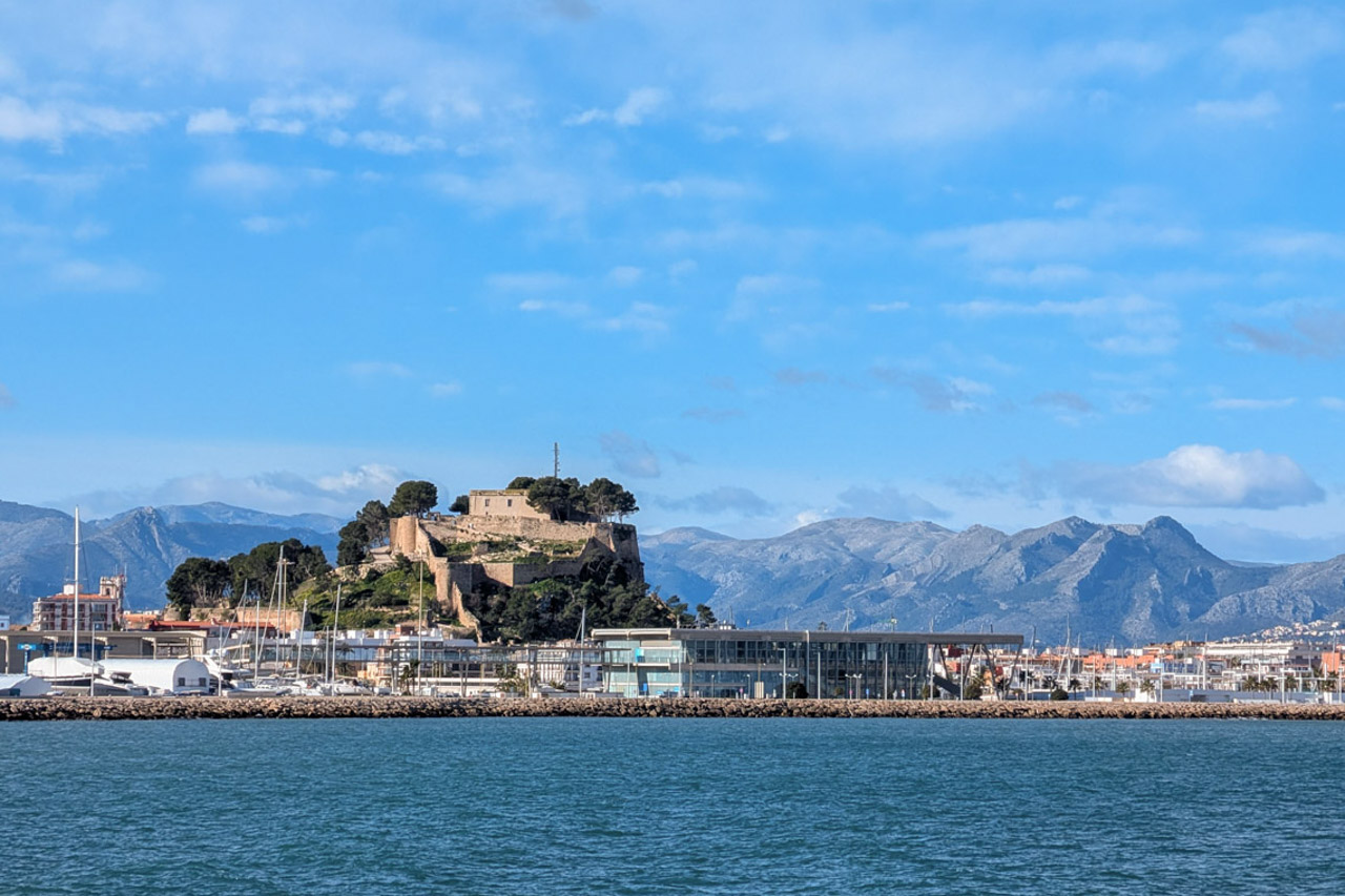 Panoramisch uitzicht op de haven van Dénia met het historische kasteel en het Montgó-gebergte op de achtergrond, gezien vanaf de zee.