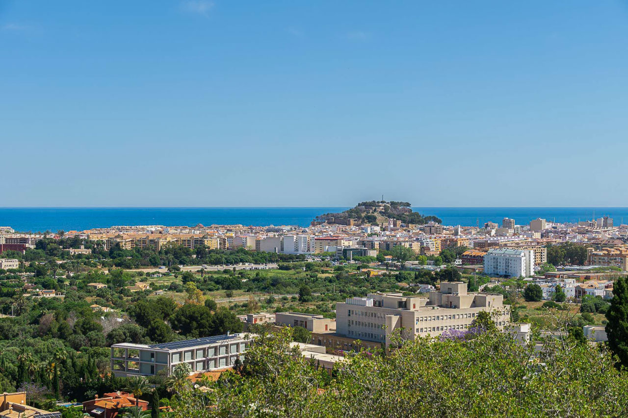 Panoramisch uitzicht over Dénia met het historische kasteel en de Middellandse Zee aan de horizon. Het verhoogde perspectief toont de nabijheid van het stadscentrum en de kust.