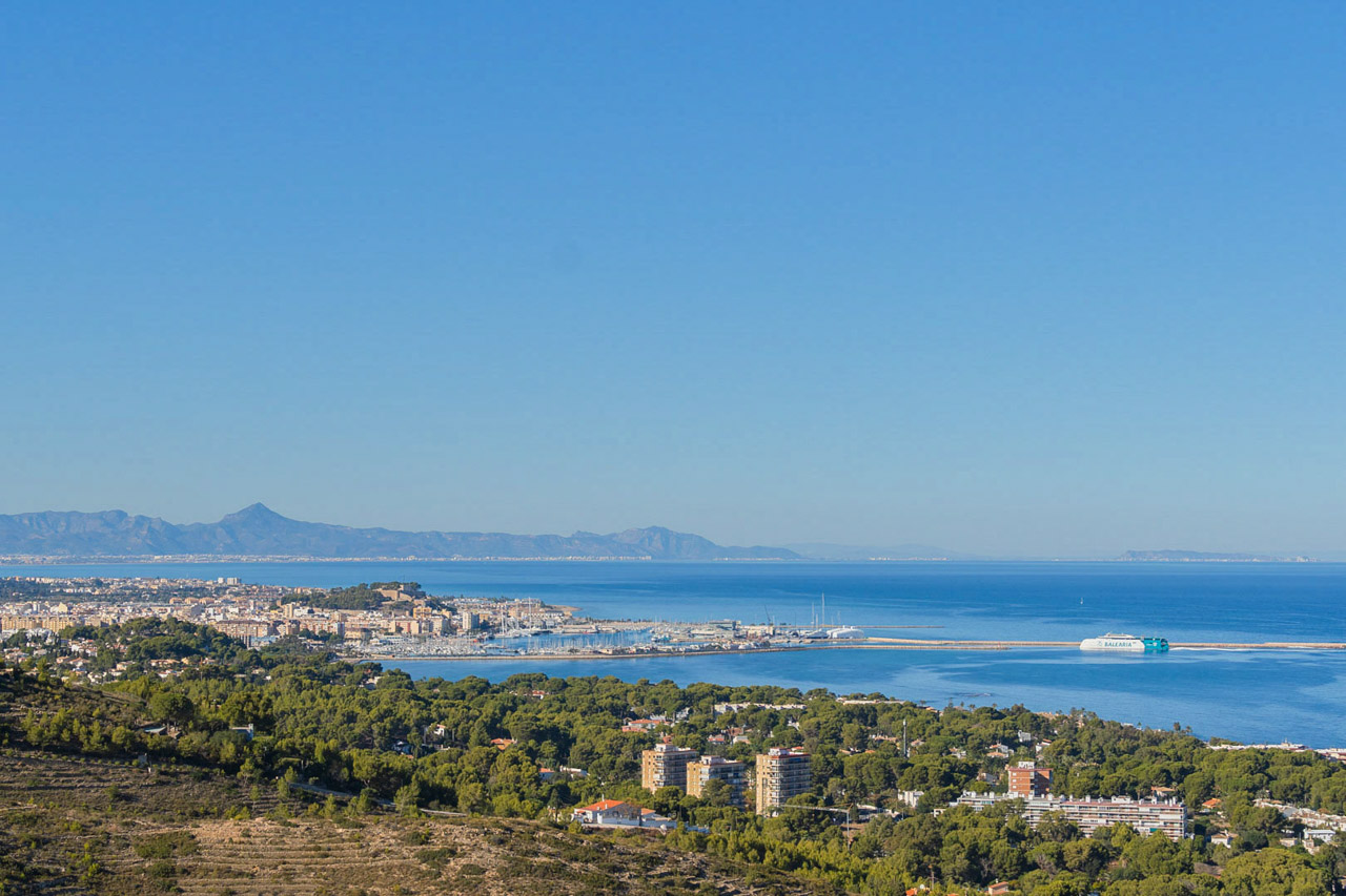 Panoramisch uitzicht vanaf de woning op de haven van Dénia en de Middellandse Zee, met het historische kasteel en de kustlijn onder een helderblauwe lucht.