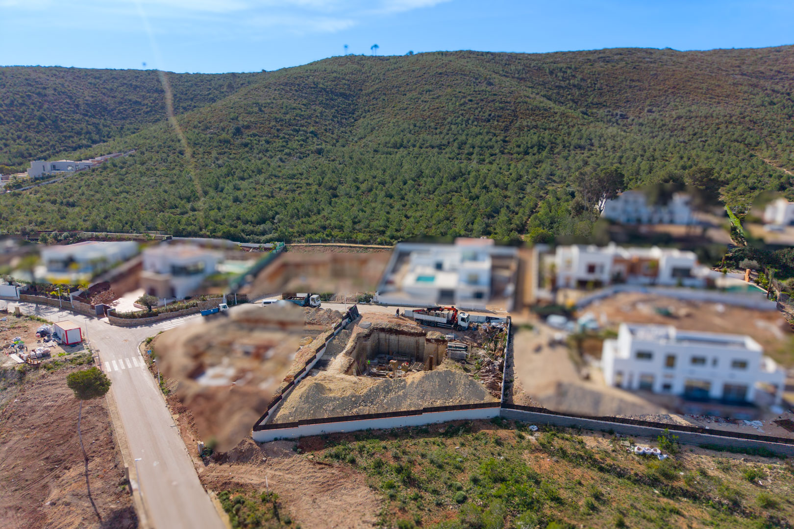 Luchtfoto van het perceel in de bouwfase, met de diepe uitgraving voor het souterrain en de fundering in een moderne woonwijk nabij de natuur van Jávea.