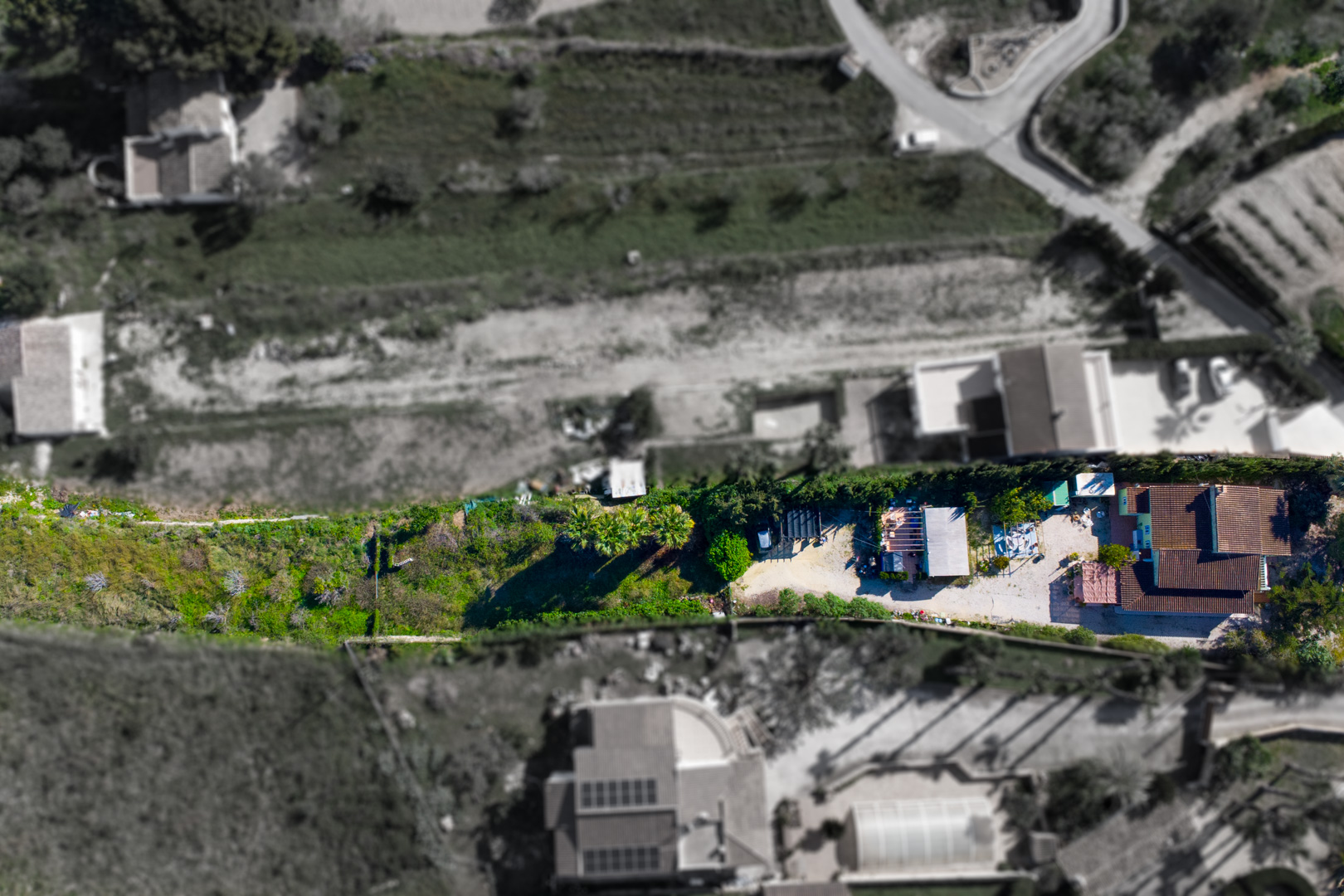 Luchtfoto van de finca met de indeling van de hoofdvilla, het prefab bijgebouw en het uitgestrekte rustieke perceel aan de rand van de vallei.