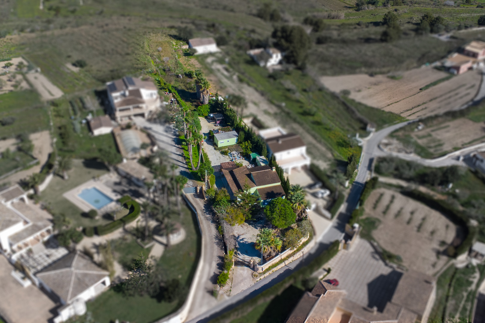Luchtfoto van het rustieke perceel van 2.800 m2 met de hoofdwoning, de geprefabriceerde unit en het uitgestrekte terrein met palmbomen.