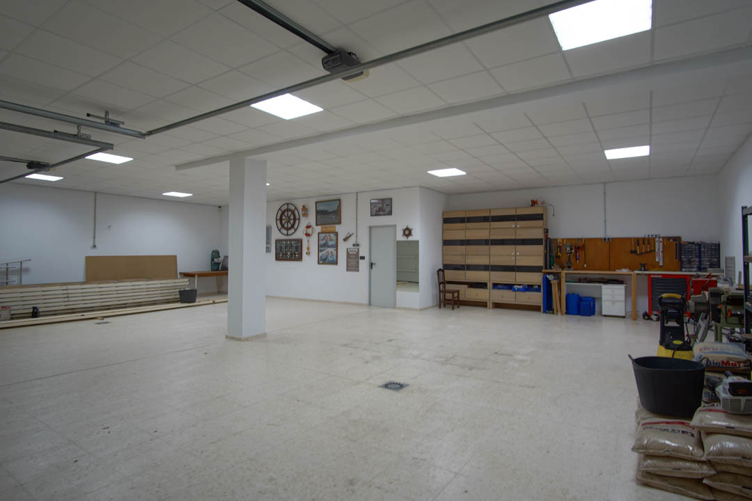 Zeer ruime garage geschikt voor meerdere auto's, voorzien van een werkplaatsgedeelte, LED-paneelverlichting en diverse opbergmogelijkheden.
