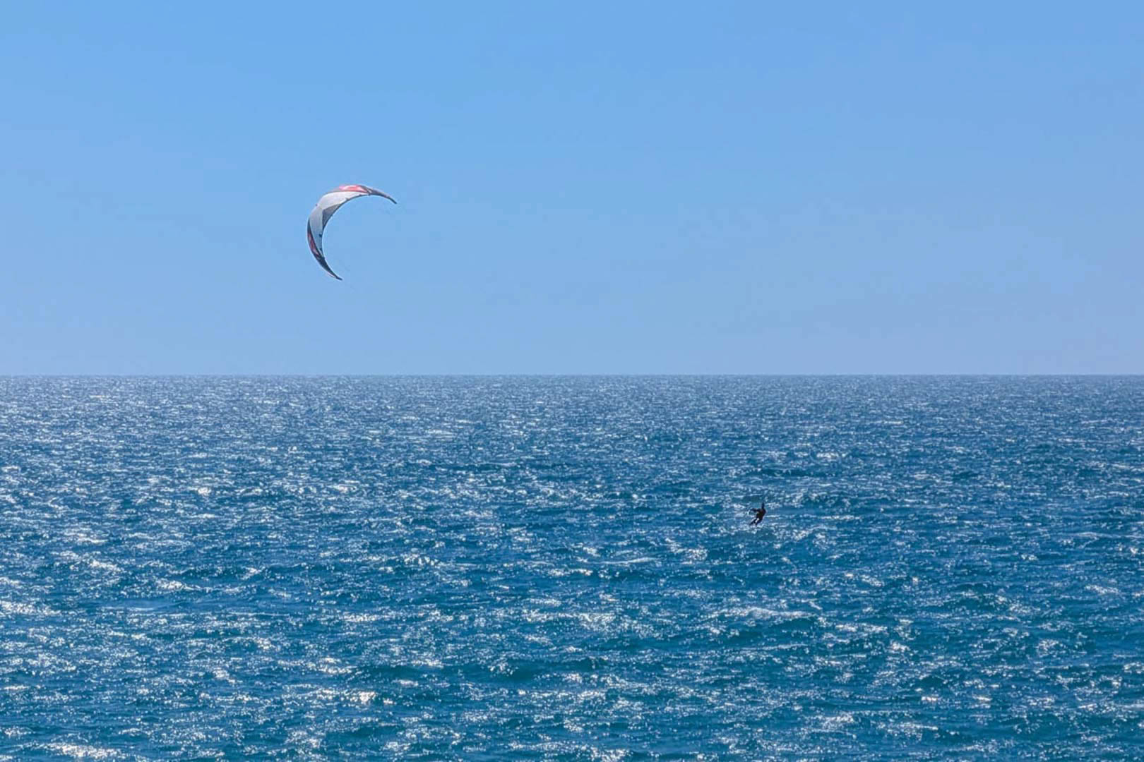 Panoramisch uitzicht over de Middellandse Zee bij Calpe, met een kitesurfer die geniet van de wind onder een helderblauwe hemel.