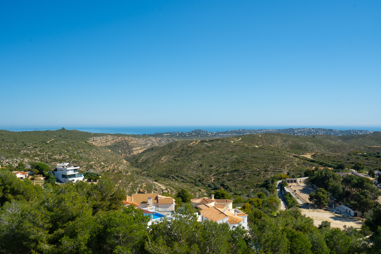 Panoramisch uitzicht vanaf de woning over het natuurpark Granadella en de Middellandse Zee, met glooiende groene heuvels en de verre kustlijn.