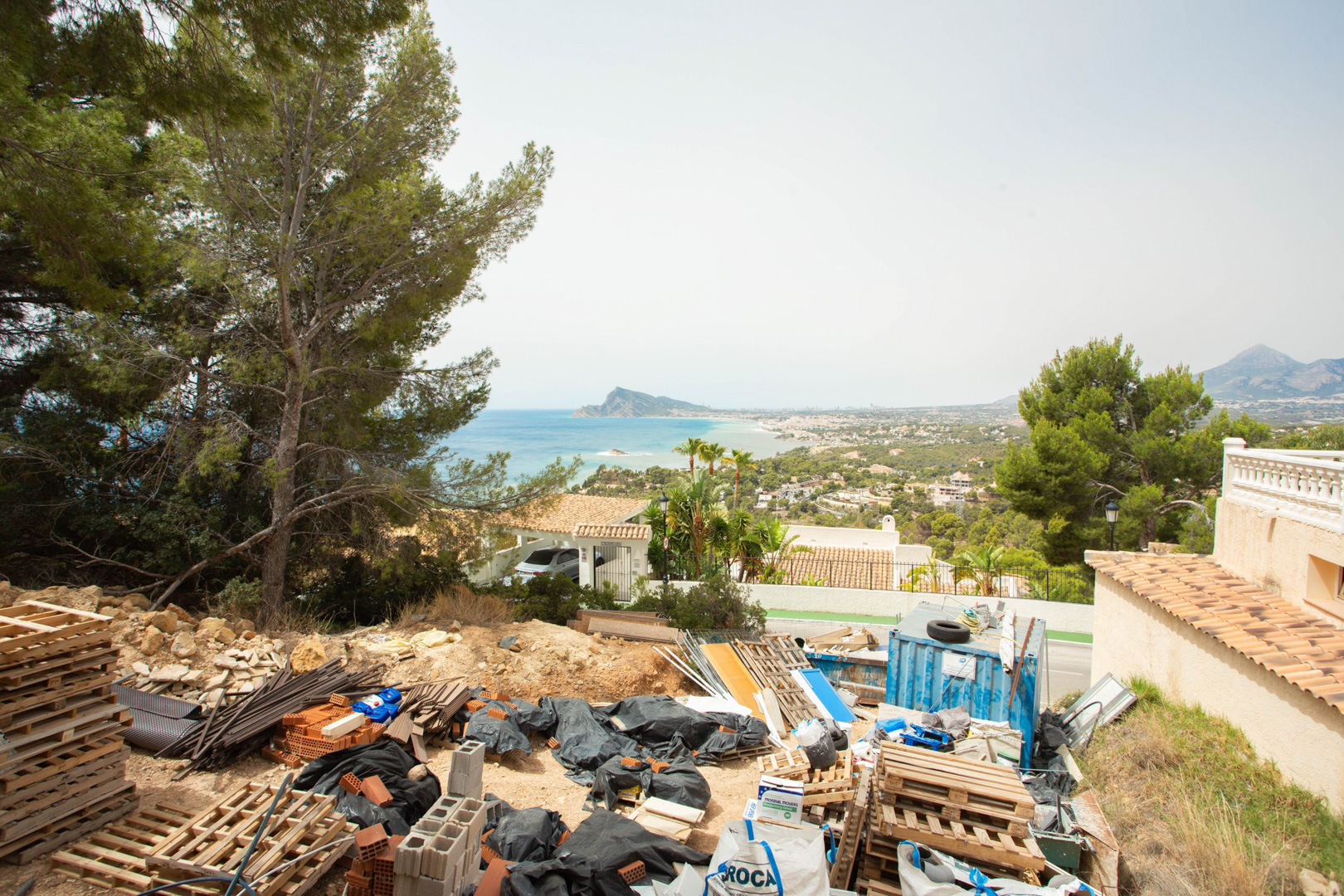 Verhoogd uitzicht vanaf het perceel in Altea Hills, met bouwmaterialen en een vrij panorama over de Middellandse Zee en de kust van Altea.