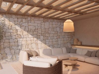 Buitenloungeruimte met natuurstenen muur, houten pergola en een ruime hoekbank. Sfeervolle verlichting en modern meubilair creëren een uitnodigende setting.