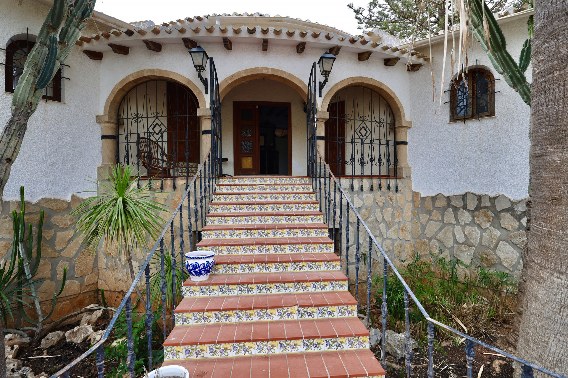 Hoofdingang van de villa met terracotta trappen en florale details.