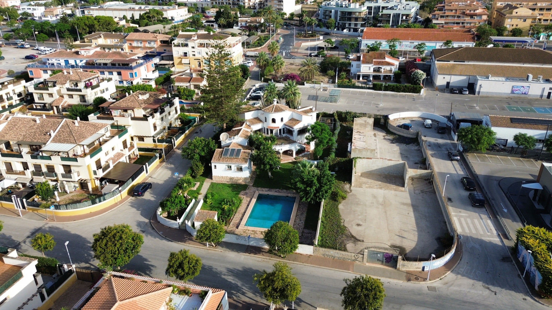 Luchtfoto van de villa met blauw zwembad omgeven door tuinen en stedelijke gebouwen in Jávea.