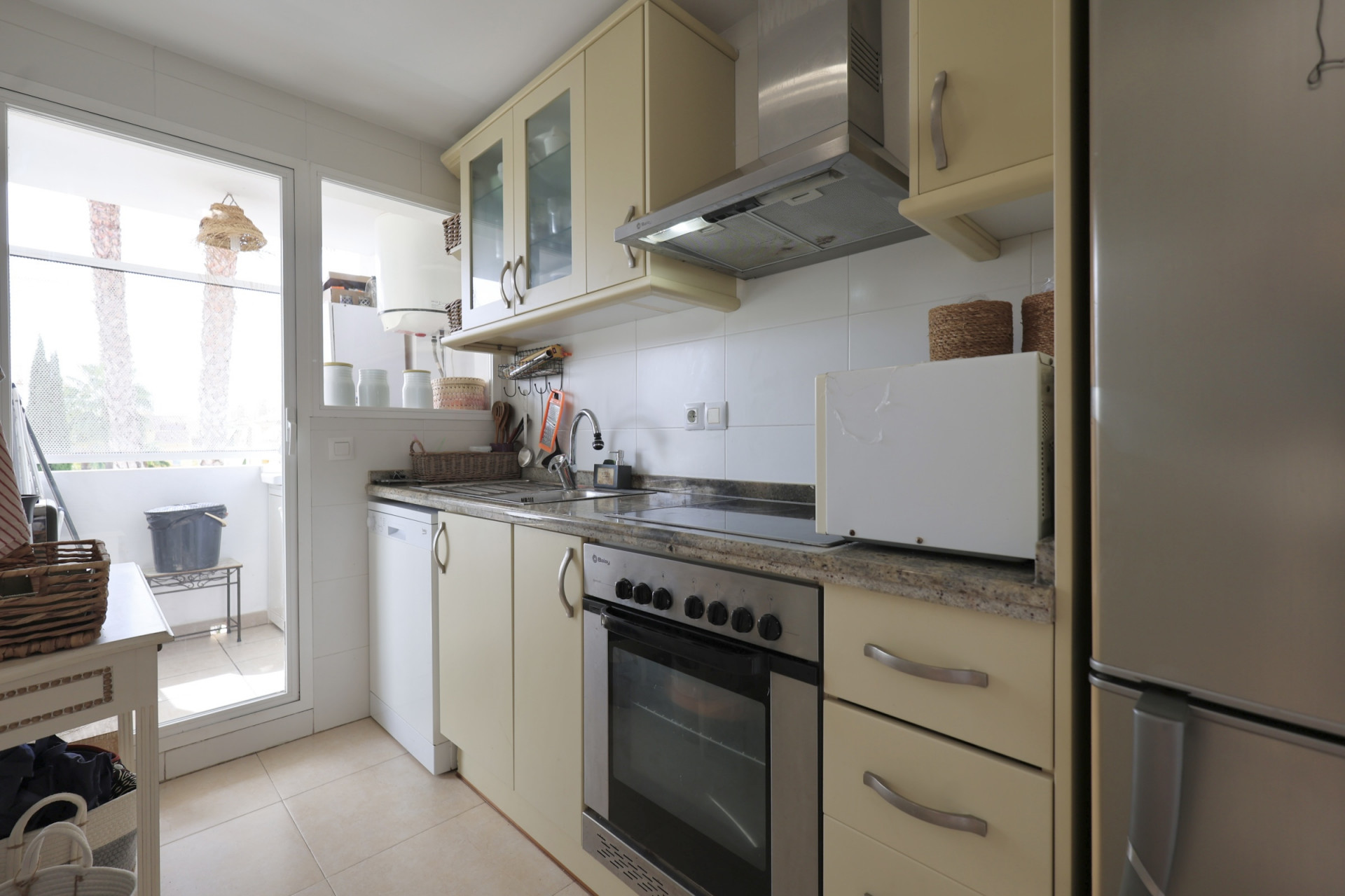 Lichte keuken met granieten aanrechtblad, roestvrijstalen apparaten en toegang tot balkon.