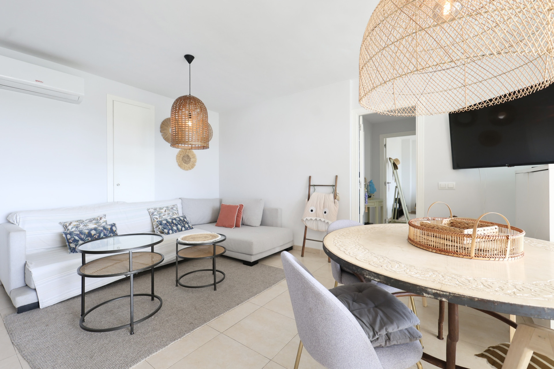 Lichte woon-eetkamer met hoekbank, rieten lampen en een design salontafel.